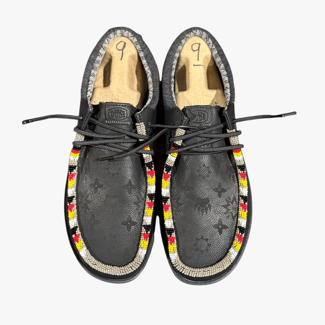 All Nations Designs &amp; More black Hey Dude slip-on shoes featuring custom hand-beaded trim and laser-etched patterns.