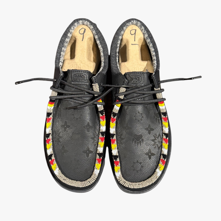 All Nations Designs &amp; More black Hey Dude slip-on shoes featuring custom hand-beaded trim and laser-etched patterns.