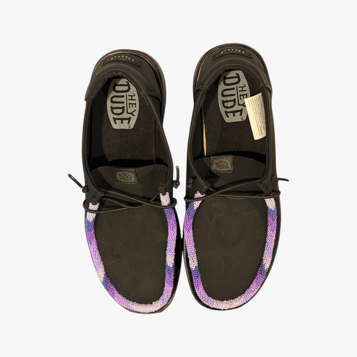 All Nations Designs &amp; More hand-beaded black leather Hey Dude Wendy X slip-on shoes with purple and white beadwork.