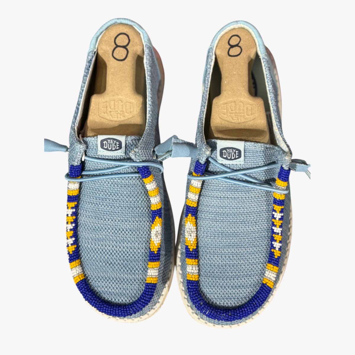 All Nations Designs & More hand-beaded blue mesh Hey Dude slip-on shoes with yellow and white geometric beadwork.