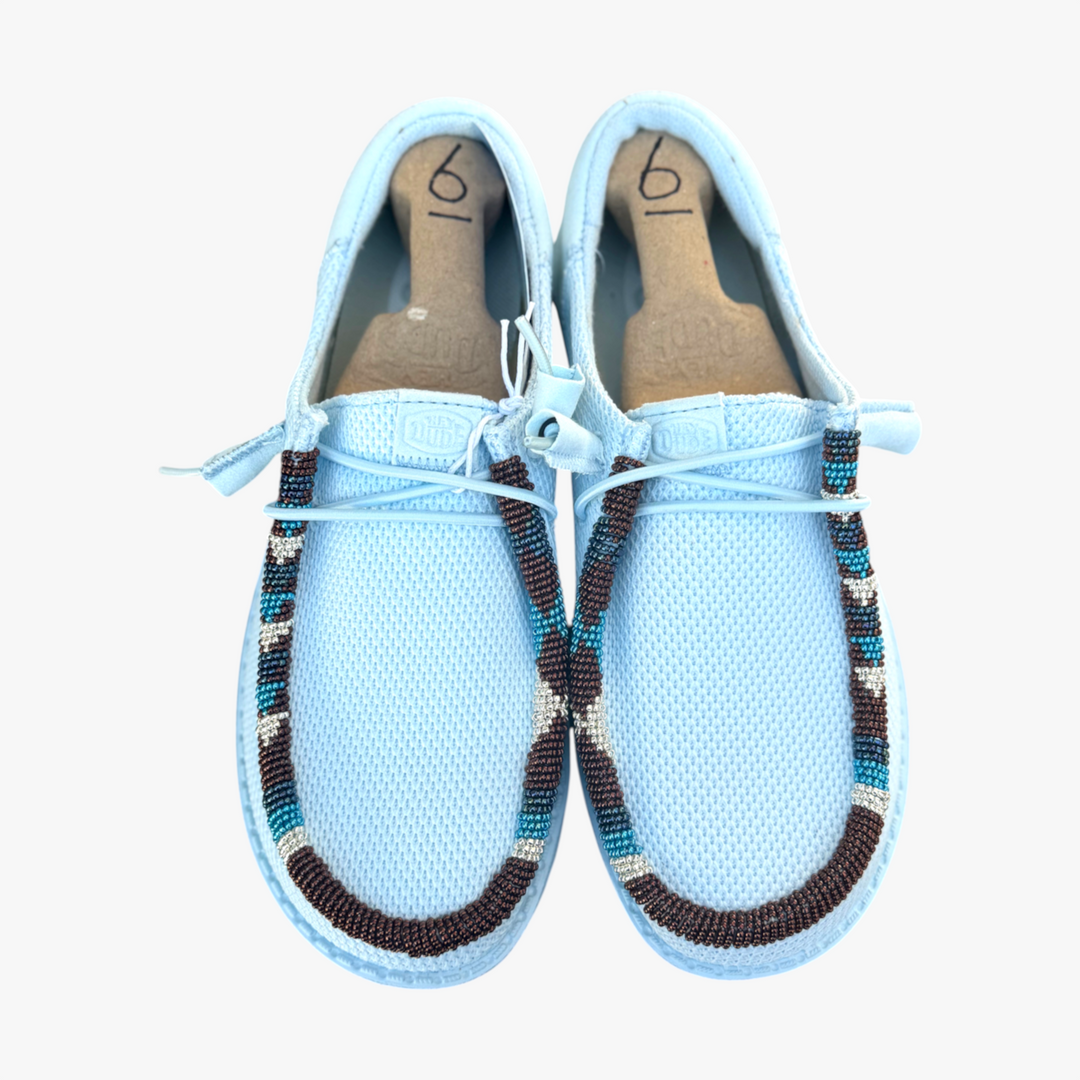 All Nations Designs &amp; More hand-beaded light blue mesh slip-on shoes with geometric brown and white beadwork detailing.