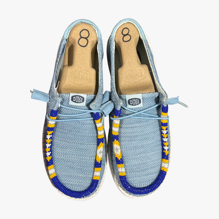 All Nations Designs &amp; More hand-beaded blue mesh Hey Dude slip-on shoes with yellow and white geometric beadwork.