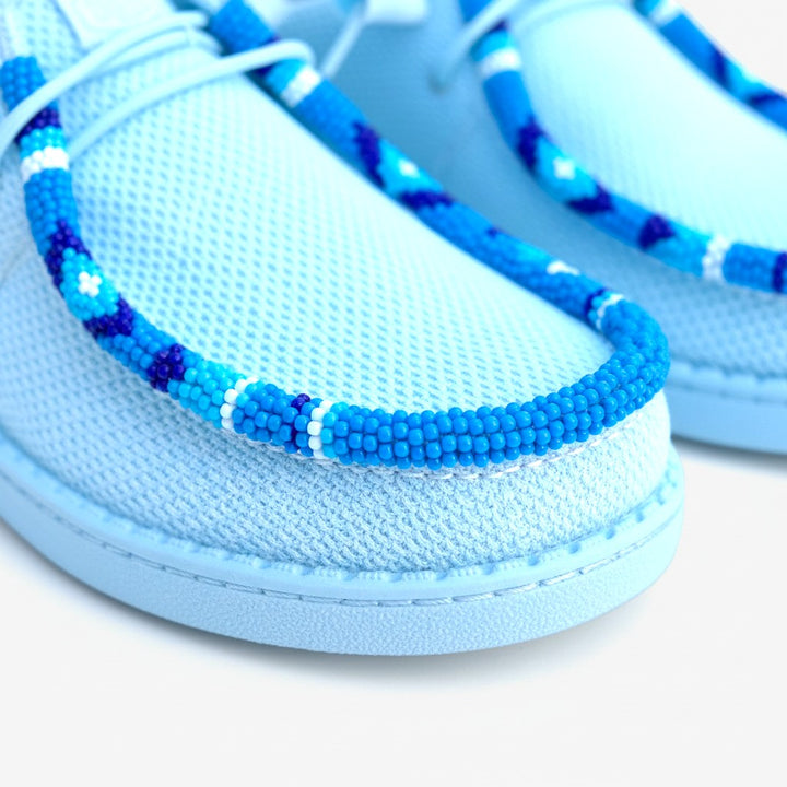All Nations Designs &amp; More hand-beaded light blue mesh slip-on shoes with intricate blue and white beadwork detailing.