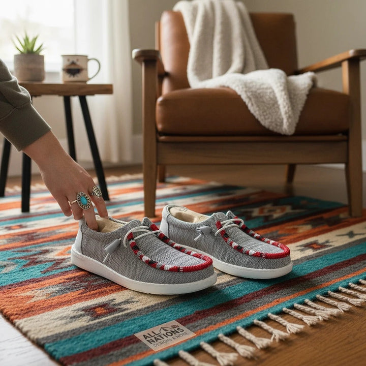 All Nations Designs &amp; More hand-beaded gray mesh slip-on shoes with red accents on a southwestern rug