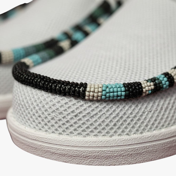 All Nations Designs &amp; More light gray mesh slip-on shoes featuring custom black, white, and turquoise hand-beaded trim.