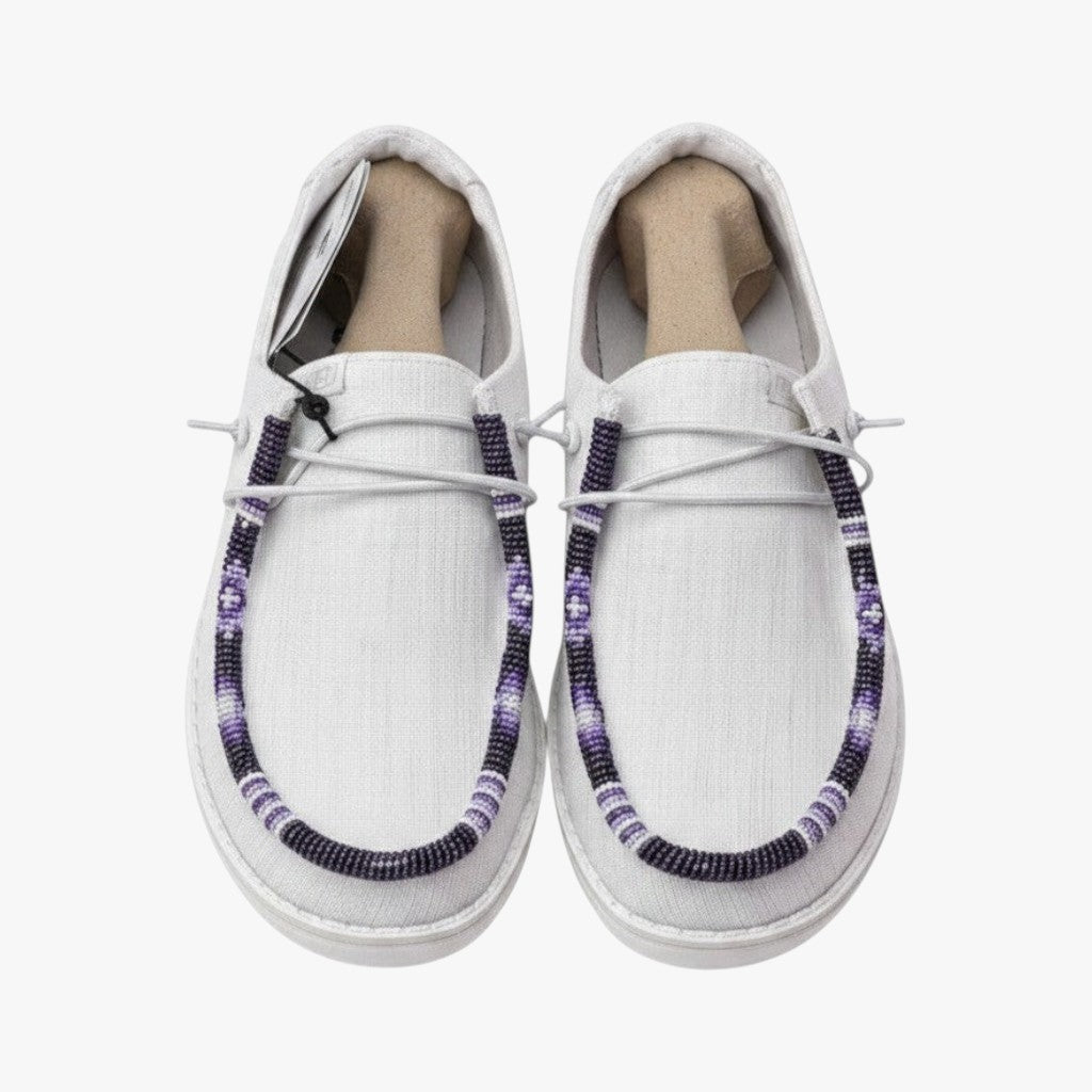 All Nations Designs &amp; More white Hey Dude slip-on shoes featuring custom purple and white hand-beaded trim details.