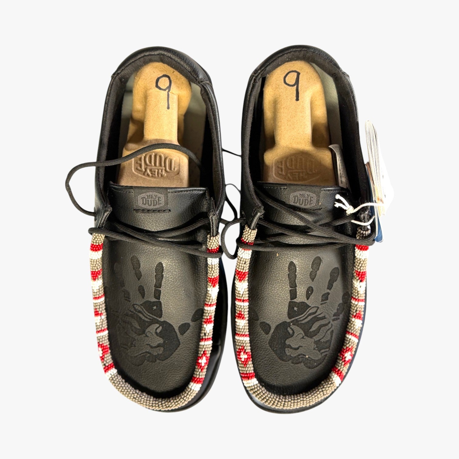 All Nations Designs & More black Hey Dude slip-on shoes with laser-etched hand prints and colorful hand-beaded trim.