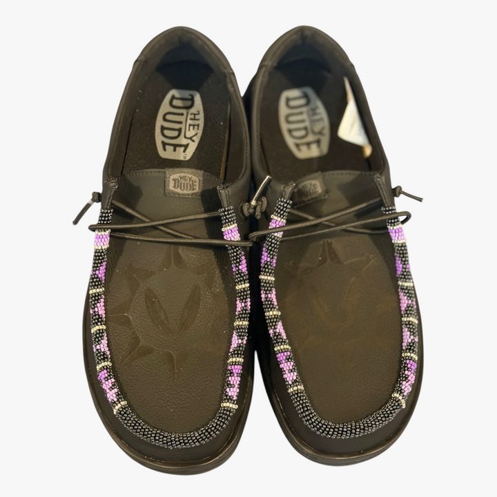 All Nations Designs &amp; More black leather Hey Dude slip-on shoes featuring custom purple and white hand-beaded detail.