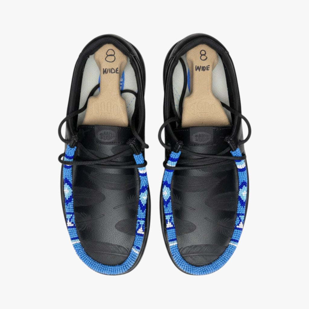 All Nations Designs & More black Hey Dude slip-on shoes featuring custom blue and white hand-beaded feather detailing.