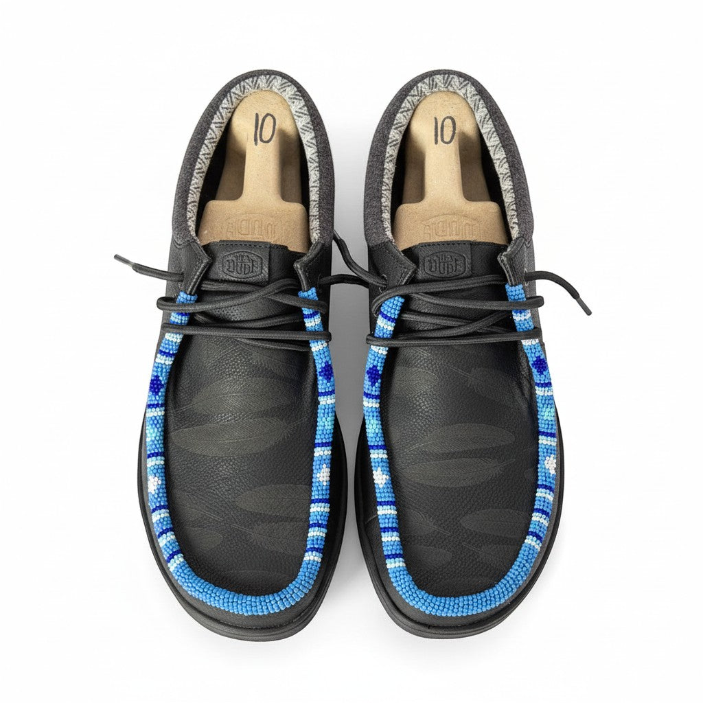 All Nations Designs & More men's black Hey Dude slip-on shoes featuring custom blue and white hand-beaded trim.