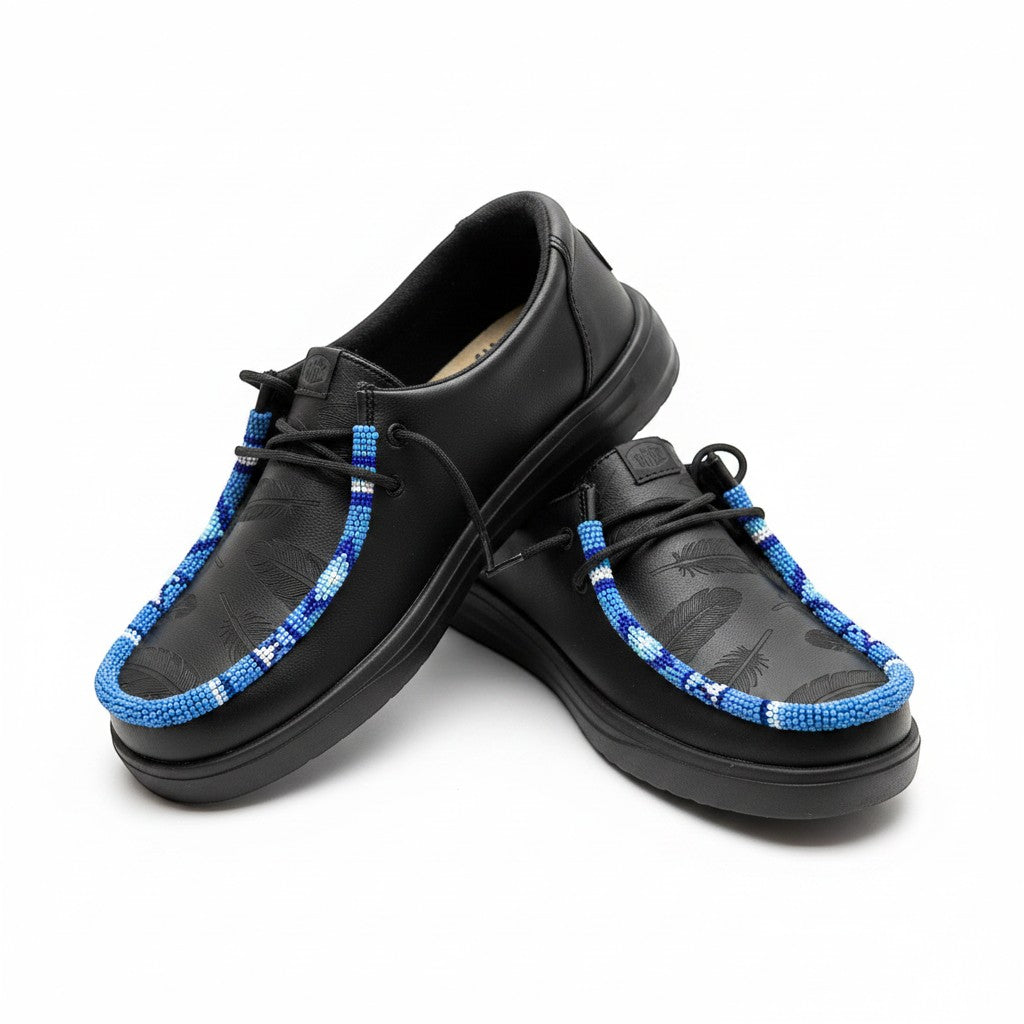 All Nations Designs &amp; More black Hey Dude slip-on shoes featuring custom blue and white hand-beaded feather detailing.
