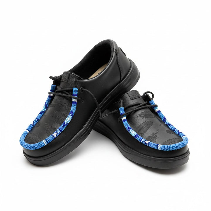 All Nations Designs &amp; More black Hey Dude slip-on shoes featuring custom blue and white hand-beaded feather detailing.