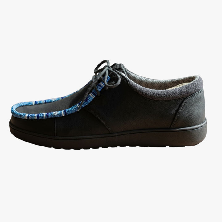 All Nations Designs &amp; More black Hey Dude slip-on shoes featuring custom blue and white hand-beaded trim on a wooden table.