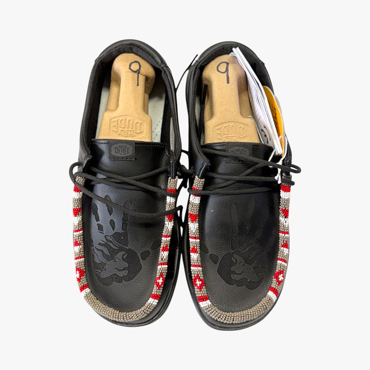 All Nations Designs &amp; More black Hey Dude slip-on shoes with laser-etched feather patterns and vibrant beadwork.