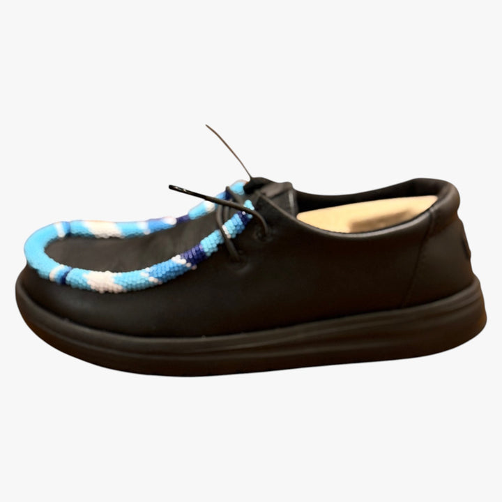 All Nations Designs &amp; More black Hey Dude slip-on shoes featuring blue and white hand-beaded trim and laser-etched detail.