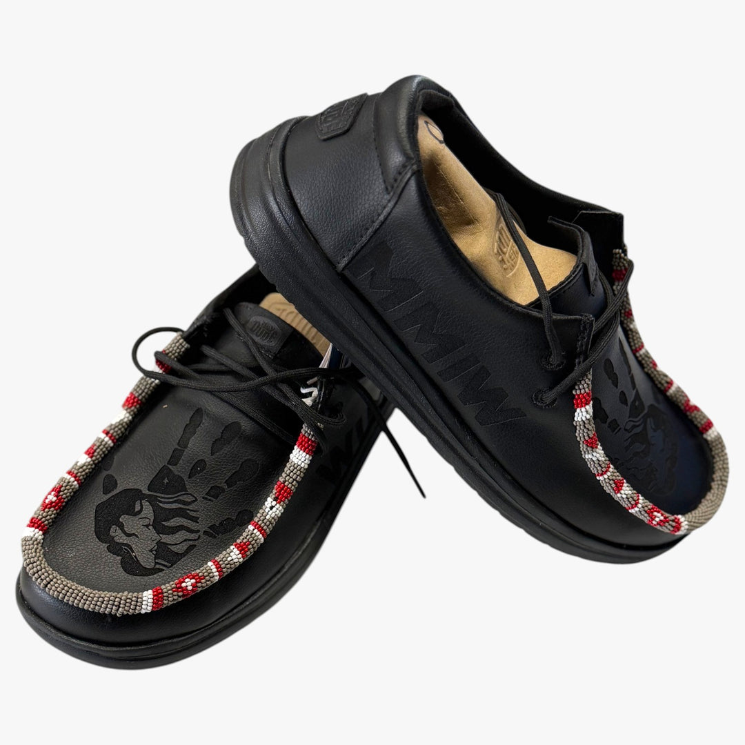 All Nations Designs &amp; More black Hey Dude MMIW slip-on shoes with hand-beaded trim and laser-etched feather design.