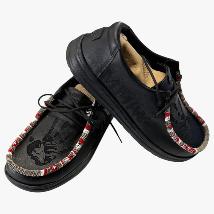 All Nations Designs &amp; More black Hey Dude MMIW slip-on shoes with hand-beaded trim and laser-etched feather design.