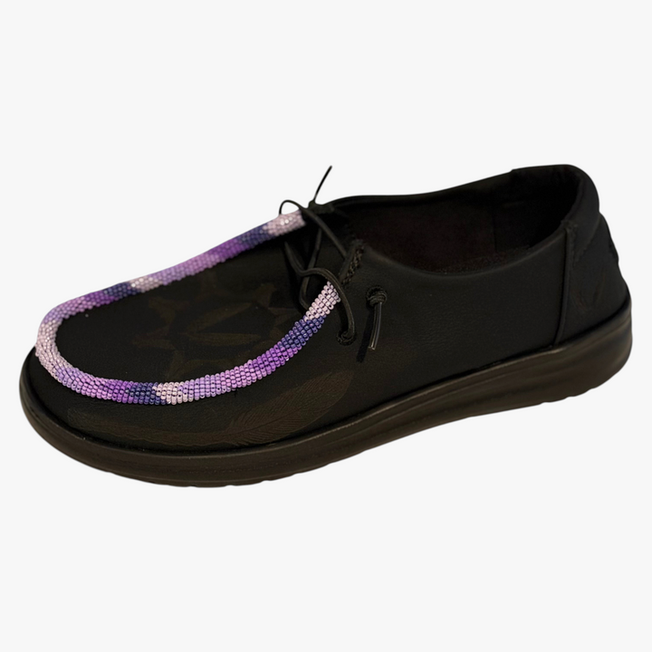 All Nations Designs &amp; More black leather Hey Dude slip-on shoes featuring custom purple and white hand-beaded trim.