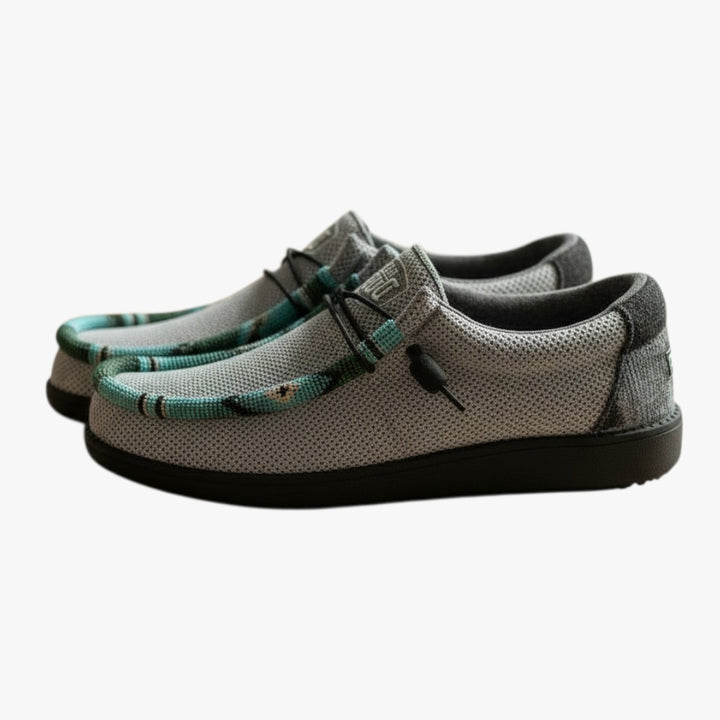 All Nations Designs &amp; More gray mesh slip-on shoes featuring unique hand-beaded detailing on a wooden surface.