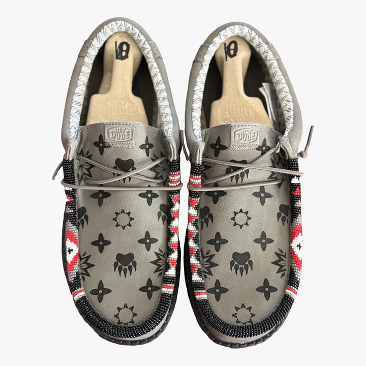 All Nations Designs &amp; More gray Hey Dude slip-on shoes featuring unique hand-beaded trim and laser-etched patterns.