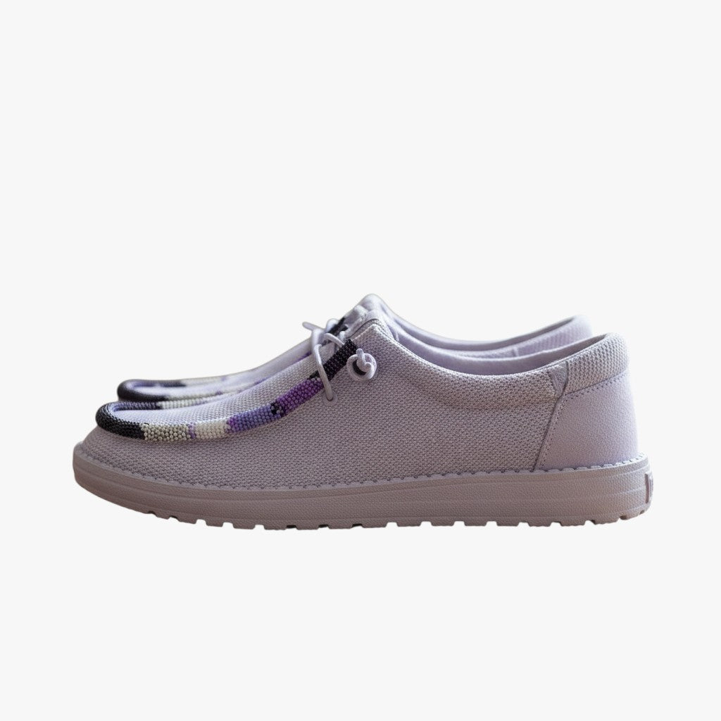 All Nations Designs &amp; More purple mesh Hey Dude slip-on shoes featuring custom hand-beaded detailing on a wooden table.
