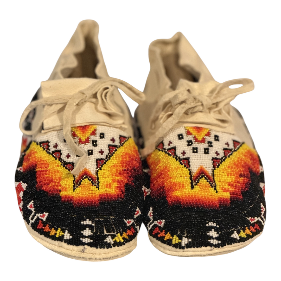 One-of-one fully hand-beaded moccasins, size 9.5, whole pair front view with black, white, yellow, orange and red beadwork
