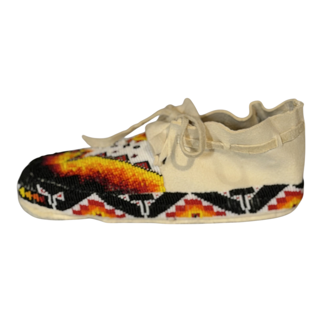 Side profile of a size 9.5 moccasin showing the beaded border and cream-colored upper