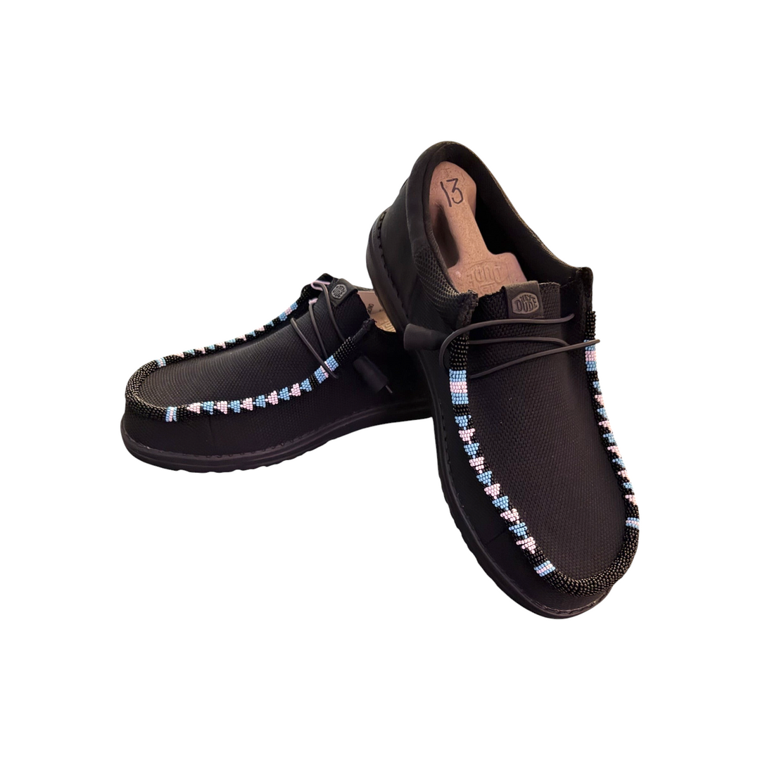 Angled view of the exact men’s size 13 black mesh Hey Dude Wally pair with black, light blue and pale pink beadwork.