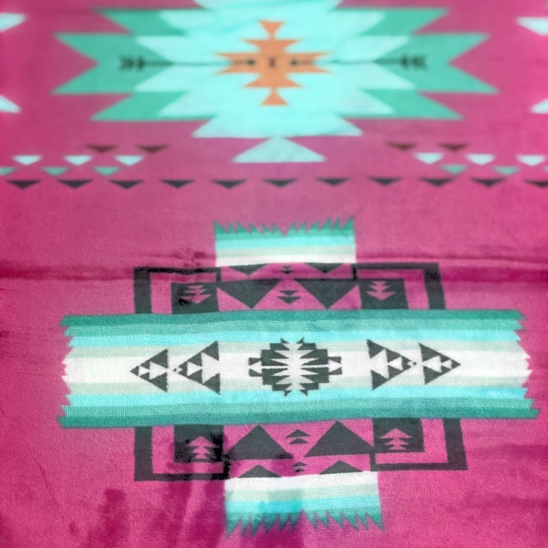 Close-up of the Hot Pink SW Sierra blanket showing bright pink fabric with turquoise, white, and black geometric pattern details.