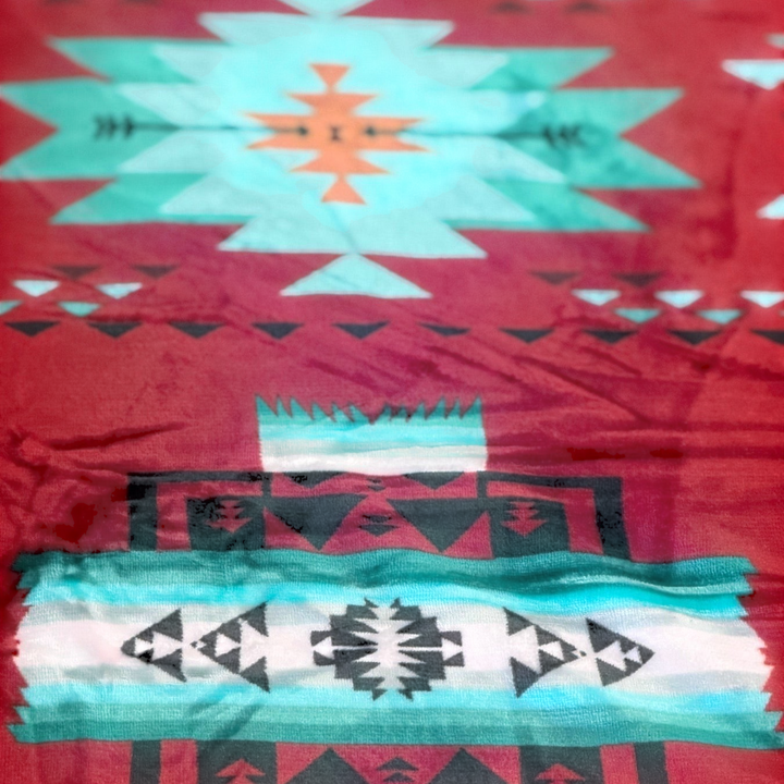 Close-up of the Red SW Sierra blanket showing red fabric with turquoise, white, and black geometric pattern details.