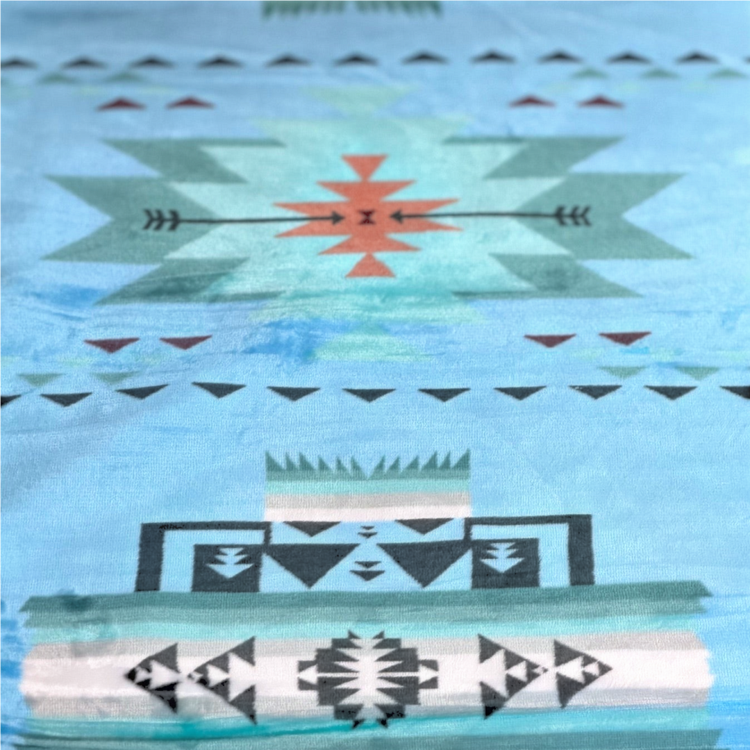 Close-up of the Sky Blue SW Sierra blanket showing its light blue fabric, stepped geometric shapes, triangles, and arrow details.