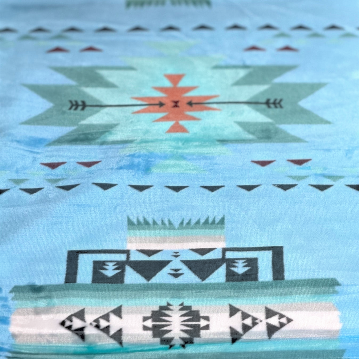 Close-up of the Sky Blue SW Sierra blanket showing its light blue fabric, stepped geometric shapes, triangles, and arrow details.