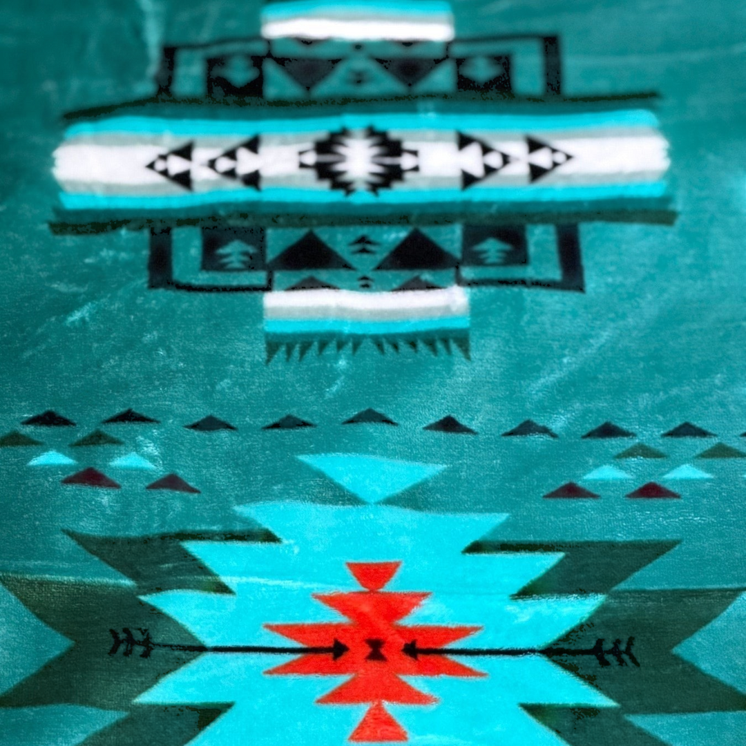 Close-up of the Turquoise SW Sierra blanket showing its turquoise fabric and contrasting black, white, and orange geometric details.