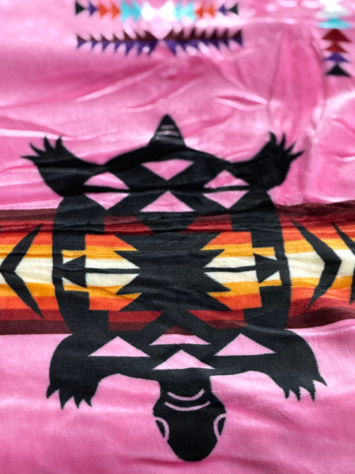 Hot Pink Turtle double-ply blanket close-up showing the turtle motif, geometric borders, and soft fabric texture.