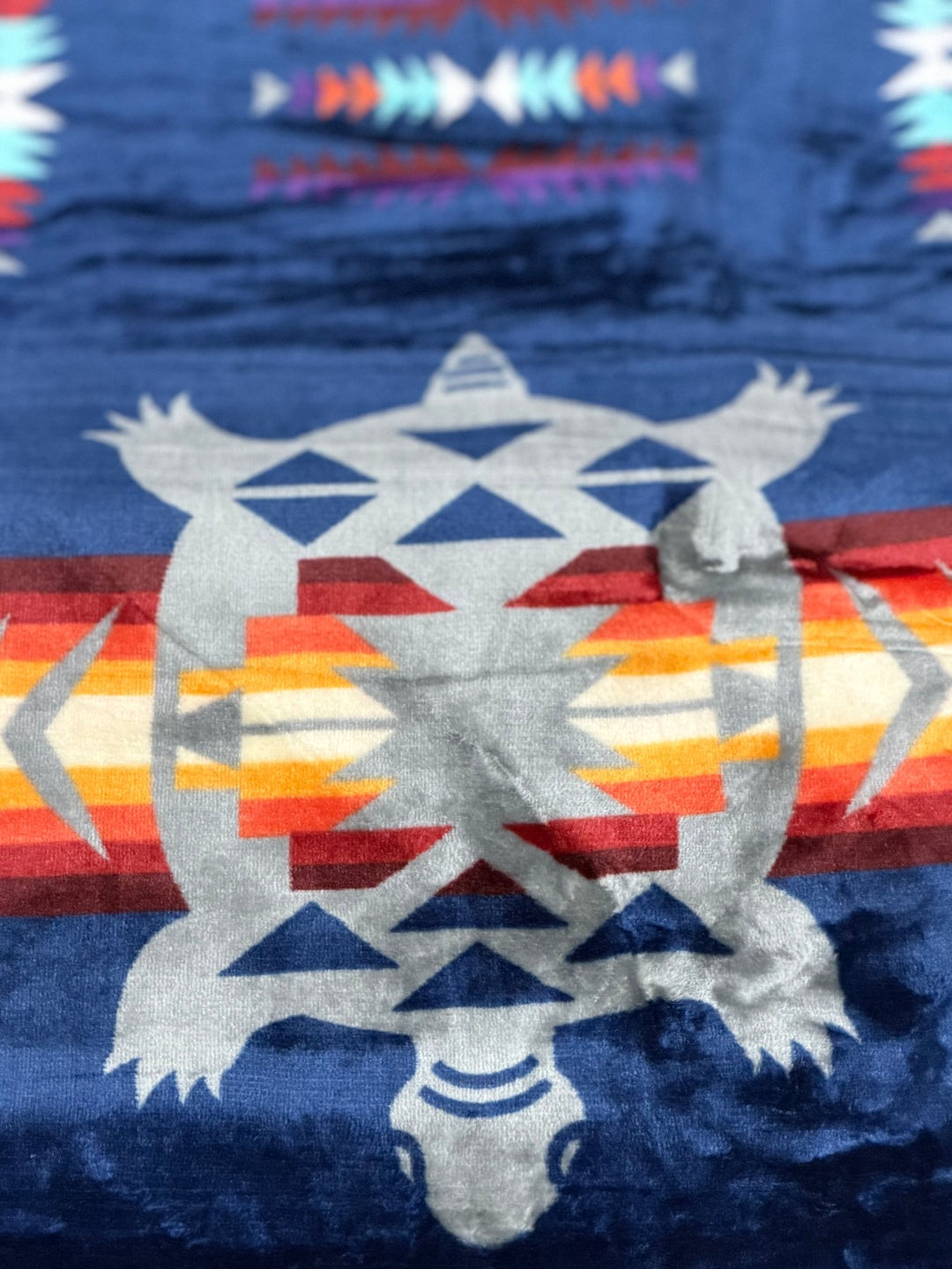 Navy Turtle double-ply blanket close-up showing the turtle motif, geometric borders, and soft fabric texture.